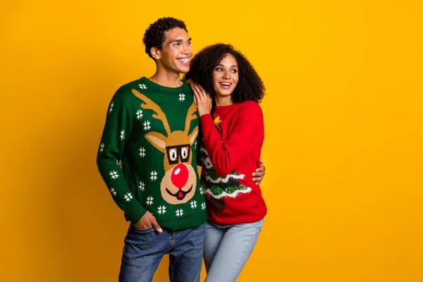 Photo of adorable pretty guy girl dressed christmas ugly print pullovers embracing looking empty space isolated yellow color background.