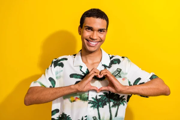 Photo of candid sincere kind man with nose piercing dressed print shirt hands show heart symbol isolated on yellow color background.