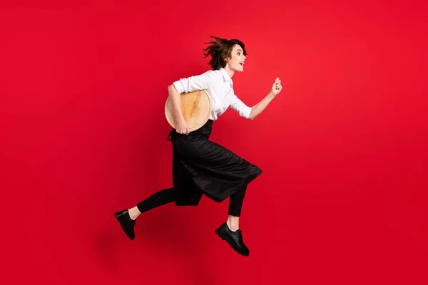 Full body profile side photo of brown bob haired woman jump up run order hurry hold tray isolated on red color background.