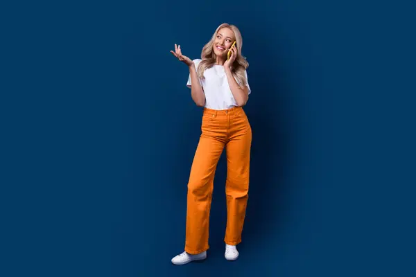 Full length photo of cute adorable girl wear trendy clothes speak phone look up empty space offer isolated on dark blue color background.