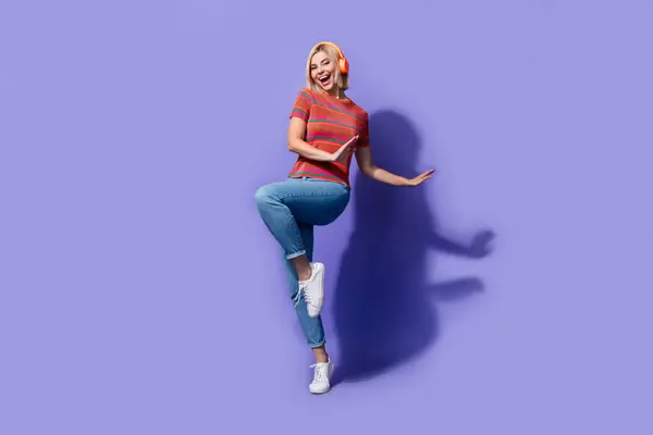 ファンキーな学生ヒップスターの魅力的な女の子のリスニングイヤホンのブーギーパーティーの写真は 紫色の背景に単独で踊るのが好きです — ストック写真