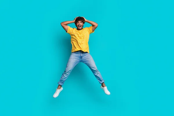 Full length portrait of impressed sporty person jumping arms touch head empty space ad isolated on turquoise color background.
