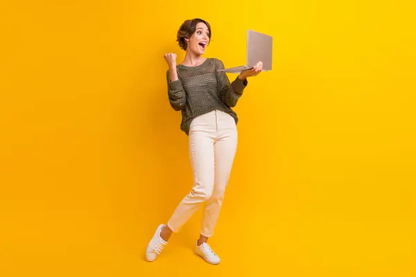 Full length photo of overjoyed crazy girl dressed trendy outfit watching video meeting online isolated on yellow color background.