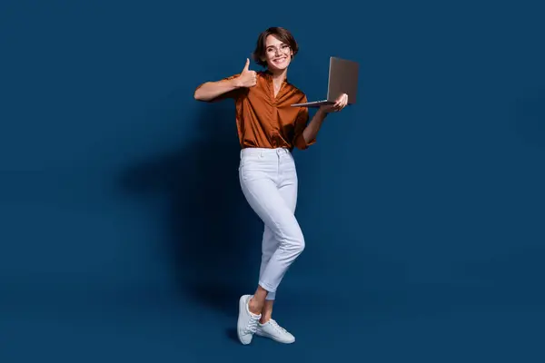 Full length photo of cool confident lady wear brown shirt showing thumb up texting modern gadget isolated blue color background.