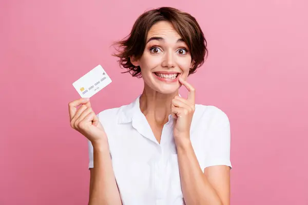 stock image Photo of funny impressed girl with bob hairdo dressed white shirt hold credit card finger on teeth isolated on pink color background.