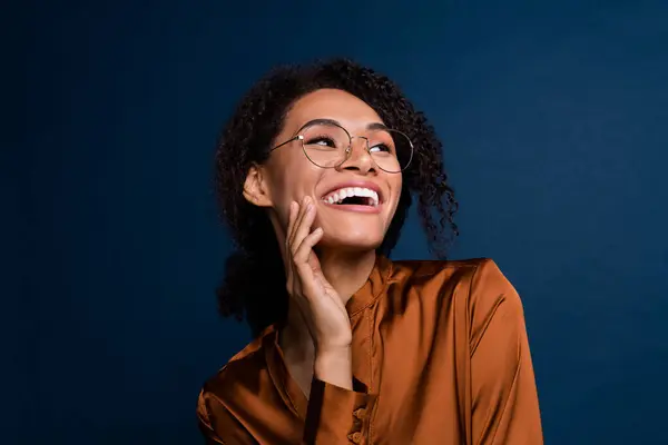 Photo of cheerful sweet woman dressed brown silk shirt eyewear looking empty space laughing isolated blue color background.