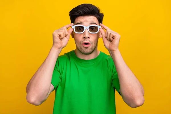 印象深刻的男人穿着时髦的T恤 触摸着3D眼镜 凝视着黄色背景下的现代视觉效果 — 图库照片