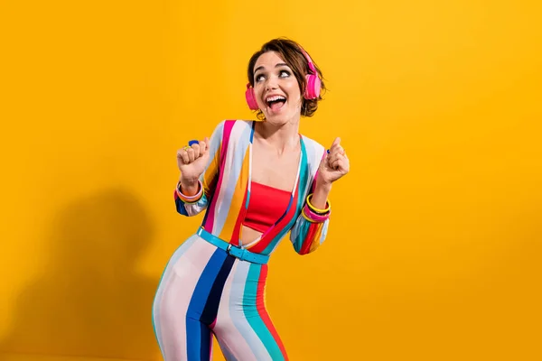 Photo of funky excited lady wear striped costume enjoying rock headphones looking empty space isolated yellow color background.