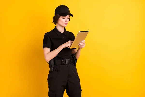 Profile portrait of calm concentrated person look finger typing tablet isolated on yellow color background.