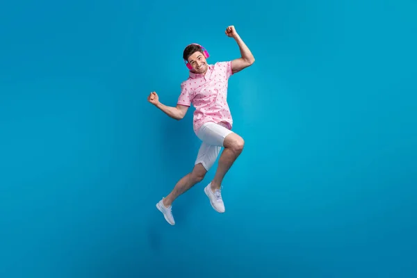 Полноразмерный Портрет Веселого Активного Мужчины Прыгающего Вверх Кулаками Слушает Музыку — стоковое фото