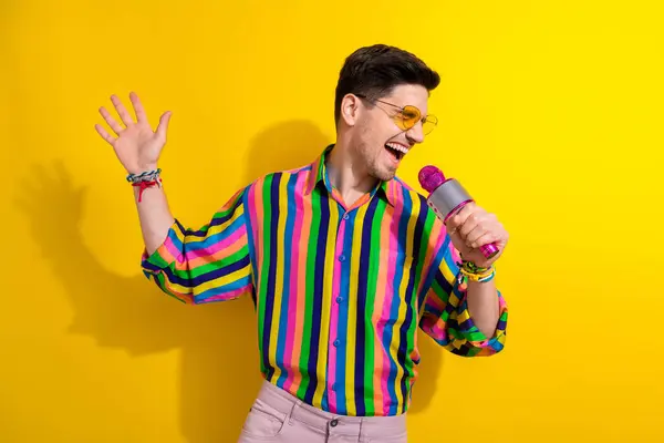 Photo of crazy young guy singing into pink mic professional singer at corporate event for employees isolated on yellow color background.