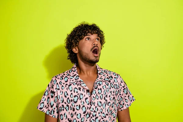 Photo portrait of nice young man look shocked up empty space wear trendy leopard print garment isolated on yellow color background.