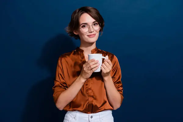 Photo portrait of lovely young lady hold coffee tea mug dressed stylish brown blouse isolated on dark blouse color background.