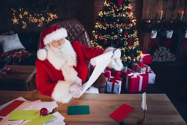 ファンキーでポジティブなサンタクロースの写真は クリスマスの願いリストを読んで赤い衣装を着ます 北極オフィスの屋内 — ストック写真
