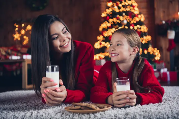 かわいい夢のような小さな姉妹の写真は 新しい年の北極の家でチョコレートビスケットを食べるカカオを飲む床に横たわる赤いジャンパーを着用します — ストック写真