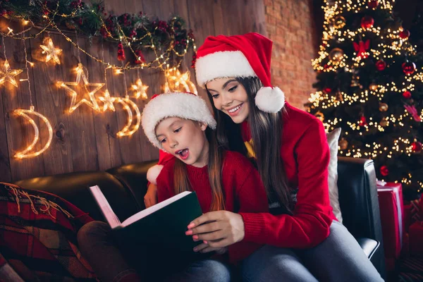 照片上 可爱的兴奋的小妹妹们穿着丑陋的印花圣诞跳楼服 抱着童话般的家庭小房间 — 图库照片