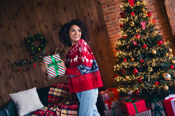 ポジティブかわいい少女歯がかった笑顔の手の写真は クリスマスのギフトボックス永遠に緑の木ライトガーランドを屋内で平らに取得します — ストック写真