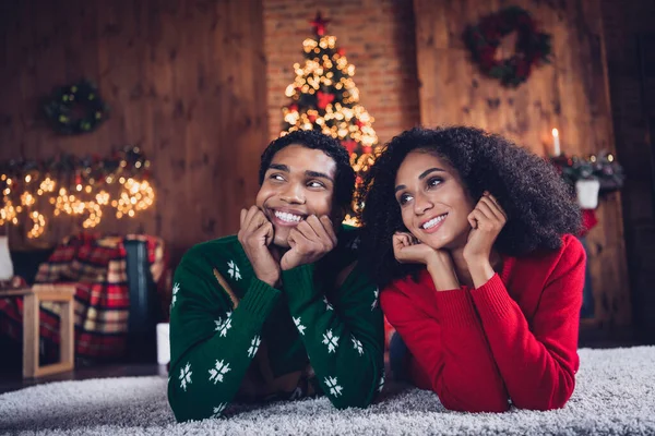 Portrait of two minded cheerful people laying carpet floor contemplate calm cozy christmas spirit decorated house indoors.