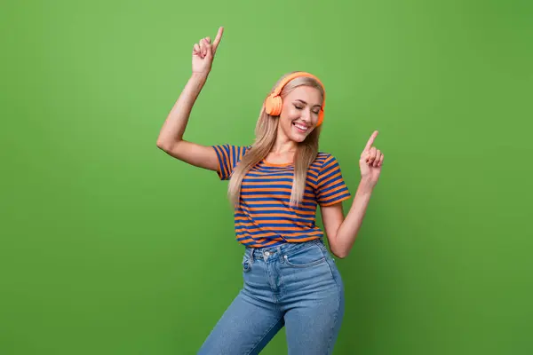 Photo of good vibes woman dancer meloman enjoying hip hop rap music in her headphones point fingers up isolated on green color background.