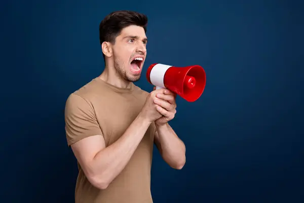 Photo of aggressive mad man wear trendy beige clothes hold bullhorn shout scream look empty space isolated on dark blue color background.