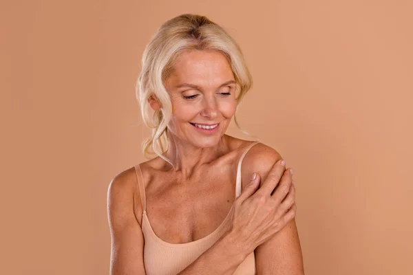 stock image Photo of dreamy cheerful middle age woman wear bikini arm touching shoulder smiling isolated beige color background.