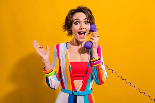 Photo of funky shocked lady wear striped costume talking vintage telephone isolated yellow color background.