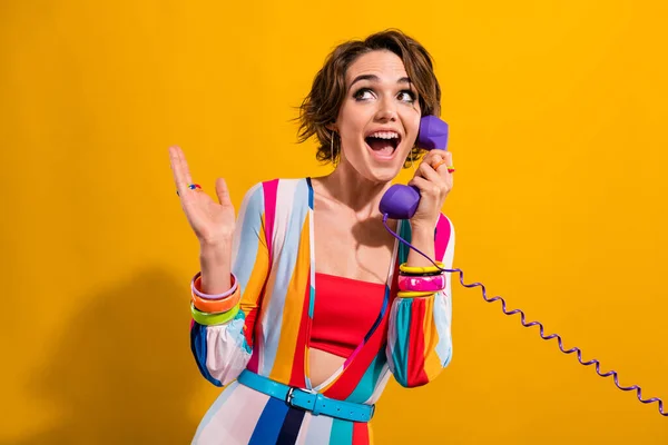 Photo of impressed funky lady wear striped costume talking phone looking empty space isolated yellow color background.