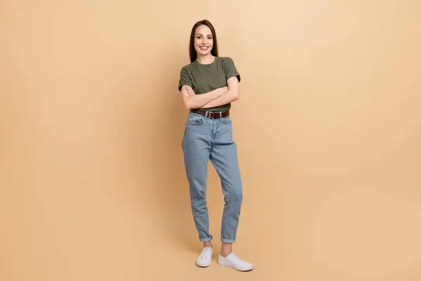 マーケティング担当の女性の折り畳まれた手のフルボディサイズの写真は ベージュ色の背景に分離された専門家のようにポーズするカーキTシャツとジーンズを着用します — ストック写真