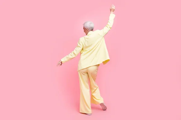 Full body photo of satisfied person dressed yellow jacket turned with her back palm raising arm up isolated on pink color background.