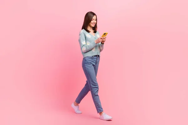 年轻影响者博客女孩用手机穿斜纹棉布牛仔裤的全长体像照片 在粉色背景下找到深情伴侣 — 图库照片