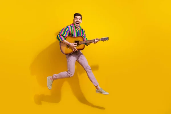 Full body photo addicted meloman professional musician guy holding guitar touching strings performance isolated on yellow color background.