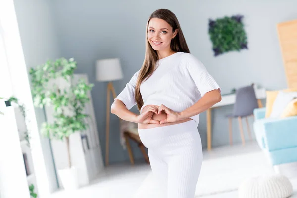 Photo of cheerful glad gorgeous lovely pregnant girl mommy mum showing heart love her baby comfort flat indoors.