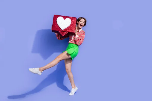 Full size photo of impressed funky woman dressed print shirt holding big social media heart in arms isolated on blue color background.