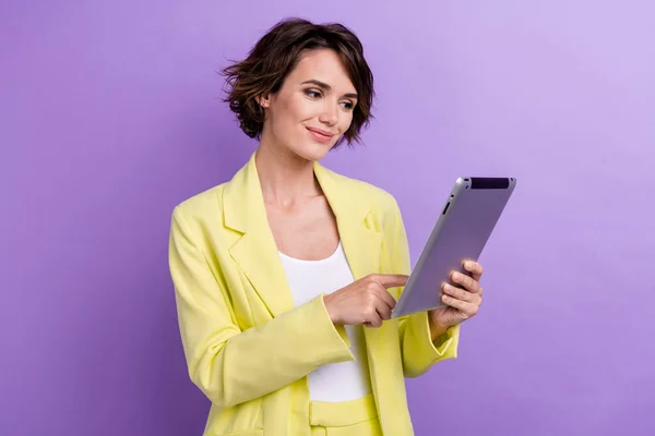 漂亮女人穿石灰漂亮衣服的肖像浏览她的平板电脑客户支持在线助理 与紫色背景隔离 — 图库照片