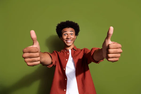 Portrait of overjoyed guy with chevelure hairdo wear stylish shirt two arms show you thumbs up nice job isolated on green color background.
