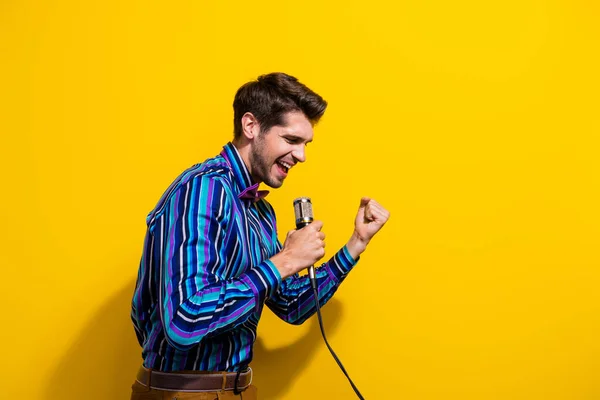 穿着时髦衬衫领带的心满意足的男人在舞台上用麦克风尖叫的画像 背景是生机勃勃的黄色 — 图库照片