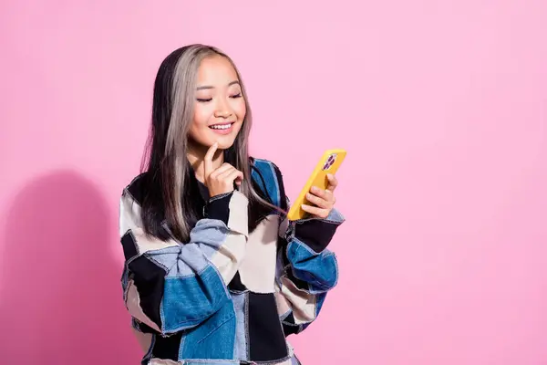 Photo of minded clever girl with dyed hair dressed pullover read email smartphone finger on chin isolated on pink color background.