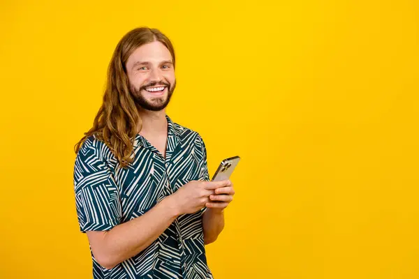 Photo of attractive funky man dressed print shirt texting instagram twitter telegram facebook empty space isolated yellow color background.