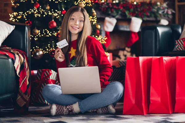 Photo of the girl near fireplace debit payment card use laptop during cashless transaction prepare gifts happy new year tradition at home.