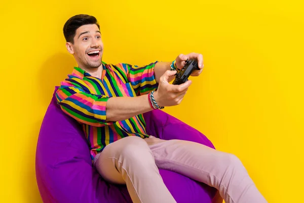 Photo of happy emotions excited man father playing at his son playstation console with wireless gamepad isolated on yellow color background.