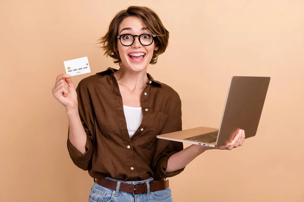 Photo of excited funky lady wear brown shirt spectacles online shopping modern device isolated beige color background.