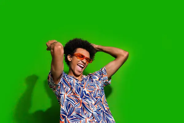 Photo of impressed cool man dressed print shirt dark glasses dancing having fun empty space isolated green color background.