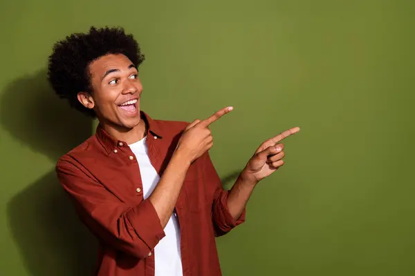 Photo of astonished man with afro hairstyle dressed brown shirt look directing at sale empty space isolated on khaki color background.