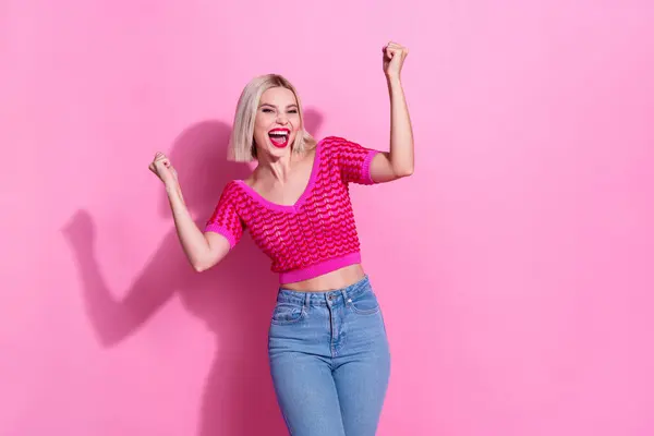 Photo of ecstatic optimistic woman with bob hairdo dressed knitwear clothes raising fists scream yeah win bet isolated on pink background.