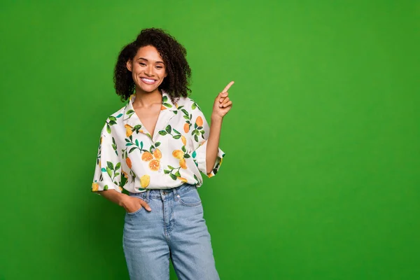 Photo of charming cute lady wear print shirt pointing finger empty space isolated green color background.