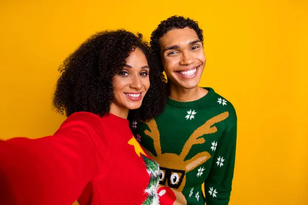 Photo of cheerful pretty guy girl dressed christmas ugly print pullovers tacking selfie isolated yellow color background.
