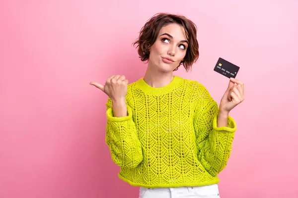 Photo of smart buyer young girl directing finger mockup holding credit card choosing cashback services isolated on pink color background.