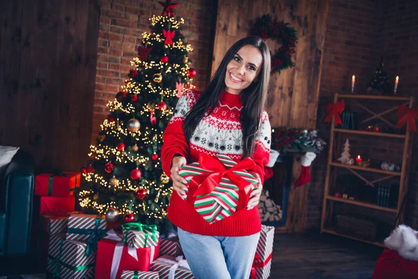 魅力的なブルネット若い女性の写真の肖像画はプレゼントボックスに装飾された装飾的なセーターのリビングルームのクリスマスの装飾を与えます — ストック写真
