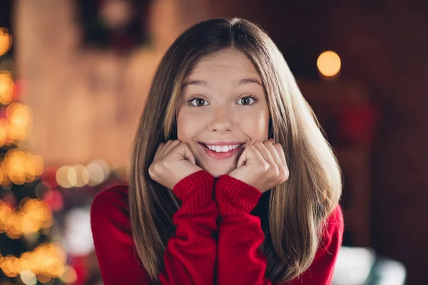Portrait of cute teen young girl in red cozy jumper touch cheeks dreaming feel safe at home during winter holidays isolated indoors.