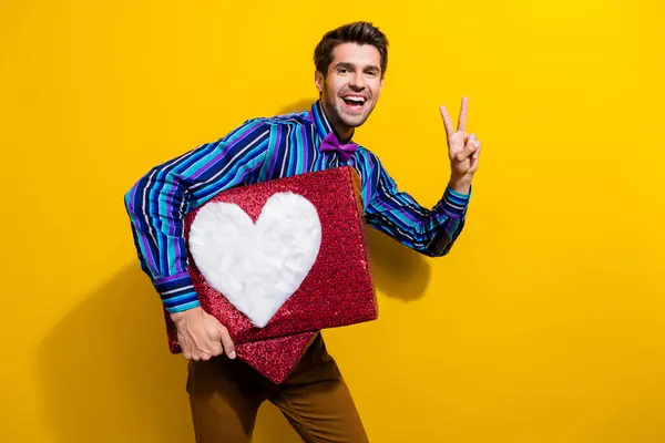 Photo of satisfied man dressed striped shirt bow tie holding big social media like show v-sign isolated on yellow color background.
